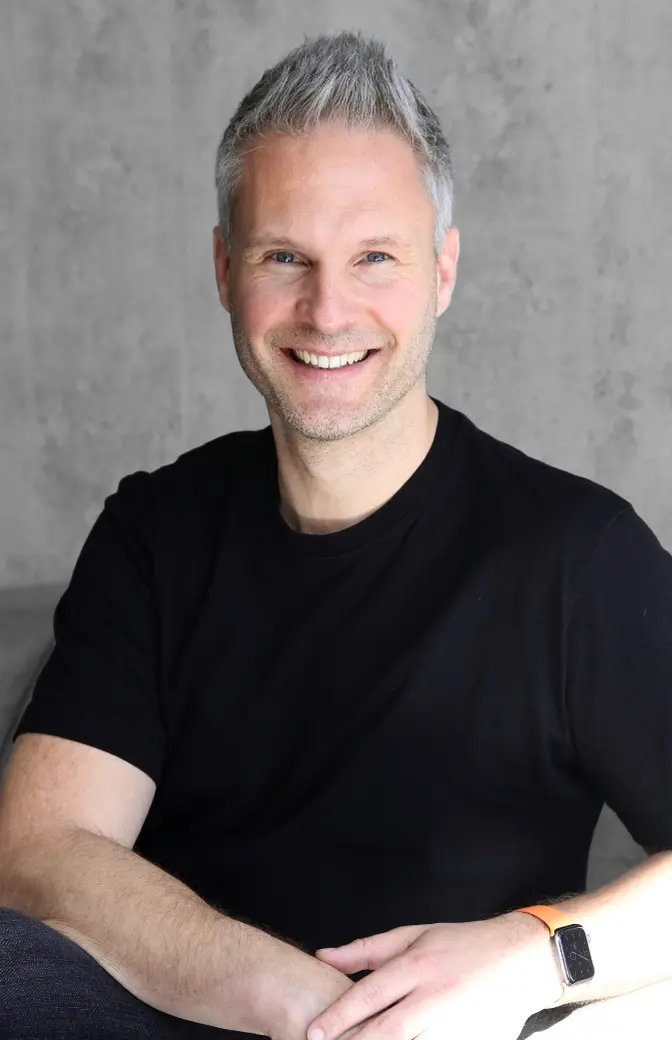 Trainer Ronnxy Rohde sitzt auf Sofa mit verschränkten Armen